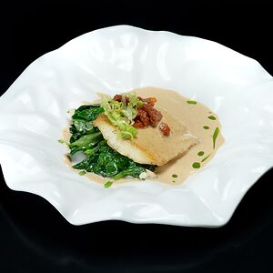 Филе судака с припущенным шпинатом, томатами, луком и соусом биск