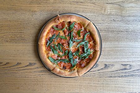 Пицца с пикантной колбасой, пармезаном, вялеными томатами и руколой