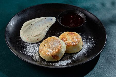 Сырники с изюмом, сметаной и брусничным соусом