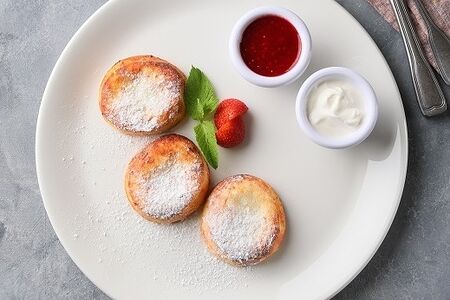 Фирменные сырники от АндерСон из свежего творога с протертой малиной и сметаной