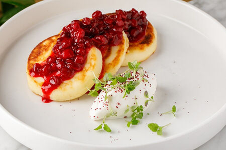 Безглютеновые сырники с чёрным изюмом, брусничным конфитюром и сметаной