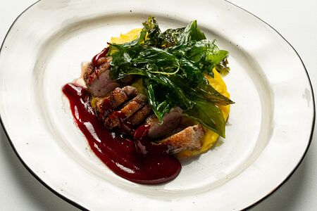 Утиная грудка с картофельным пюре, малиново-винным соусом и листьями трав во фритюре