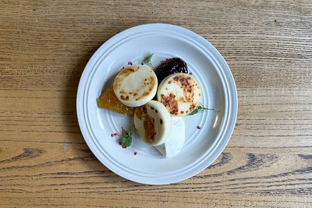 Творожные сырники с апельсиновым конфитюром, брусничным взваром и домашней сметаной