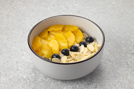 Овсяная каша с голубикой, персиком и миндальными лепестками