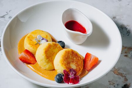 Сырники с кремом из вареной сгущенки и соусом из черной смородины