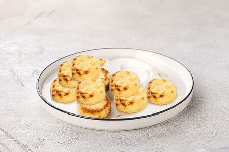 Большая порция сырников со сметаной и вишневым вареньем