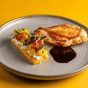 Запеченная куриная грудка, полента, творожный крем, обжаренные томаты, пряный апельсин, чили