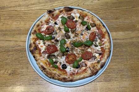 Пицца с морепродуктами, томленными в белом вине, каперсами, маслинами и томатами черри