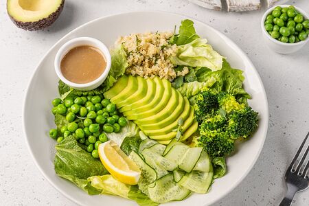 Большой зеленый салат с авокадо, киноа, брокколи, свежими огурцами, молодым горошком и шпинатом