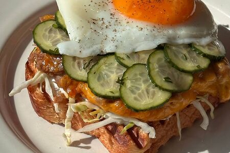 Открытый сэндвич на бриоши с запеченной индейкой, глазуньей и огурчиками