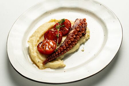 Осьминог с пюре из запеченного картофеля и обжаренными томатами