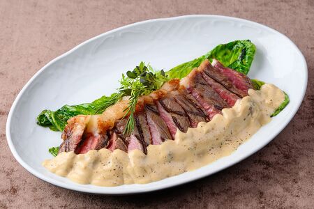 Стейк стриплойн с кремом из печеного чеснока и листьями романо на гриле