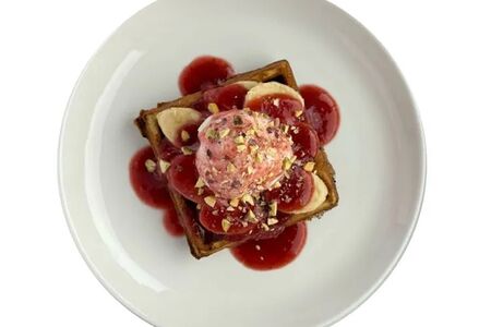 Сладкая вафля с мороженым, бананом и клубничным соусом