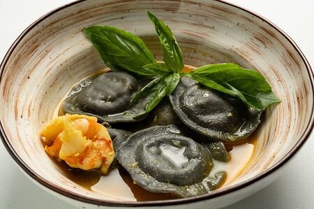 Черные равиоли с начинкой из дорадо и креветок в рыбном бульоне с шафраном 