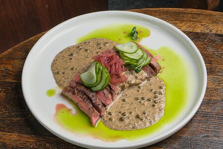 Фланк-стейк с перечным соусом, маринованным в джине огурцом и маринованным красным луком