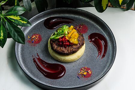 Сочный бифштекс из мяса буйвола, приготовленный на огне с картофельным пюре и пряным брусничным соусом 