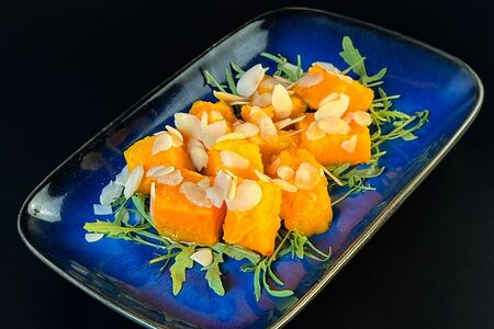 Печёная тыква, обжаренная на сливочном масле на подложке из рукколы