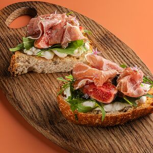 Брускетта на заквасочном хлебе с прошутто, хурмой, руколой, лимонной рикоттой, трюфельным медом