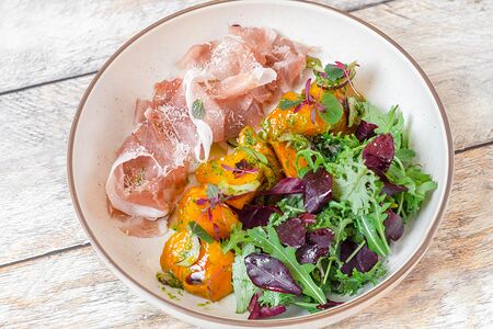 Салат с прошутто, хурмой и соусом песто