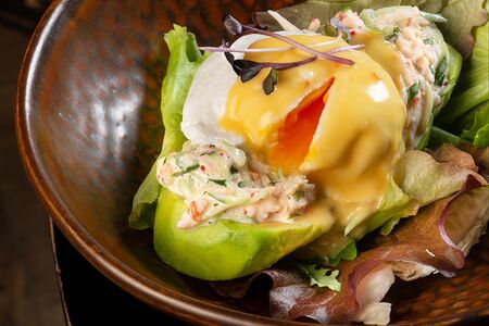 Салат с крабом, яйцом пашот и тобико в половинке авокадо