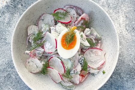 Салат овощной из огурца, редиса, томата и лука, украшается яйцом и заправляется сметаной