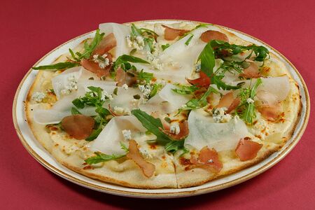 Пицца с дыней, пармской ветчиной, сыром дорблю и свежей рукколой на сливочно-винном соусе