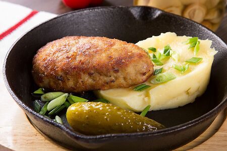 Мясная котлета с пюре и соленым огурцом