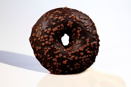 Пончик-донат с глазурью из темного шоколада с кусочками молочного шоколада