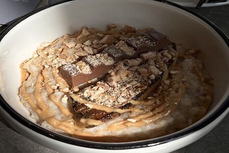 Овсяная каша на миндальном молоке с ломтиком киндер шоколада, арахисовой пастой и карамельным бананом