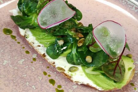 Брускетта с мягким сыром, авокадо, листьями салата и тыквенными семечками