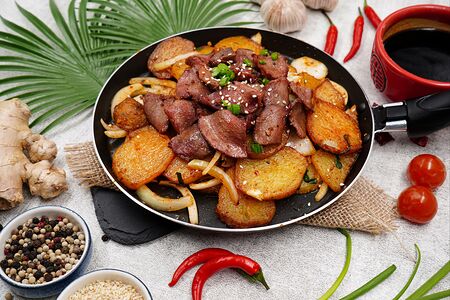 Острые куриные желудки с картофелем на горячей сковороде