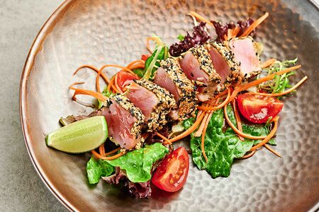 Татаки с тунцом на подушке из томатов черри с листьями салата и паназиатской заправкой