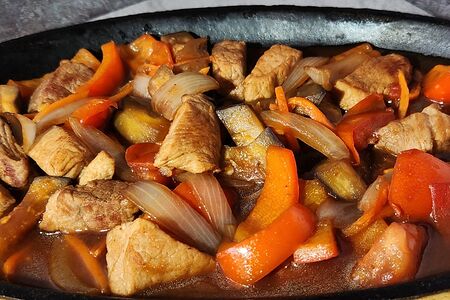 Шипящая сковородка со свининой и овощами в остром соусе