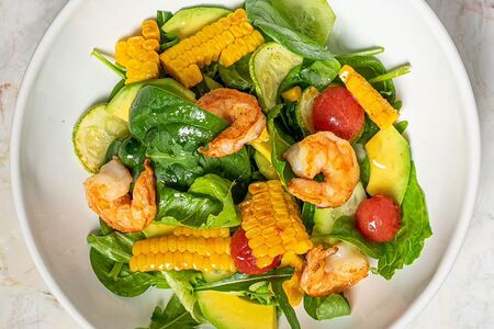 Салат с обжаренными креветками, цукини и кукурузой на гриле, огурцом, авокадо и черри