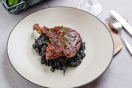 Утиная ножка конфи на подушке из гречотто с белыми грибами и чернилами каракатицы