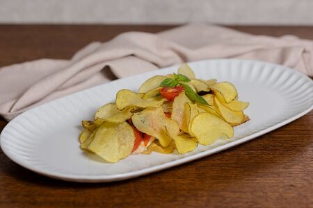 Сибас под хрустящим картофелем с томатами