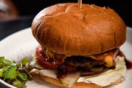 Сочный бургер с котлетой из буйвола, сыром чеддер, овощами и картофелем фри