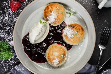Сырники со сметаной и соусом из черной смородины