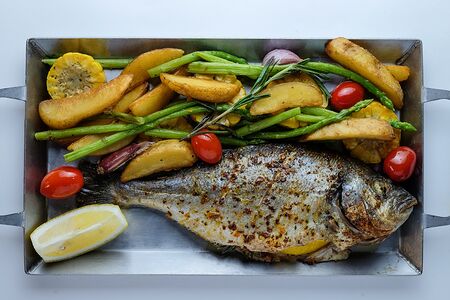 Дорадо со спаржей, картофельными дольками, кукурузой и томатами черри