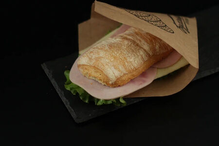 Сэндвич с ветчиной, сыром и зеленью в булочке панини