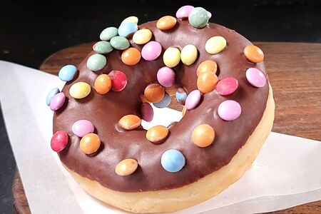 Пончик-донат с шоколадной глазурью и цветными драже