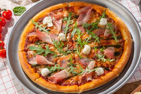 Пицца с ветчиной прошутто, руколой и молодым сыром